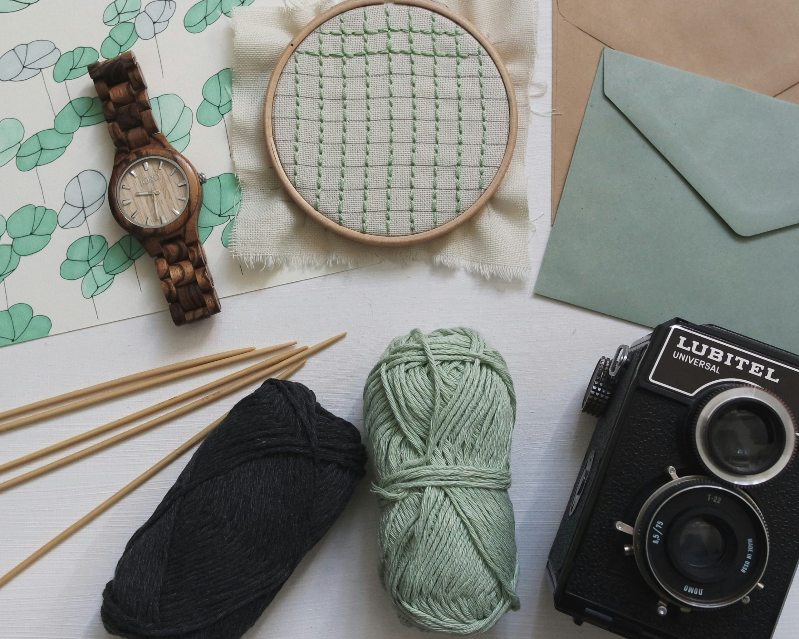 yarn, needle point, a camera, knitting needles and envelopes