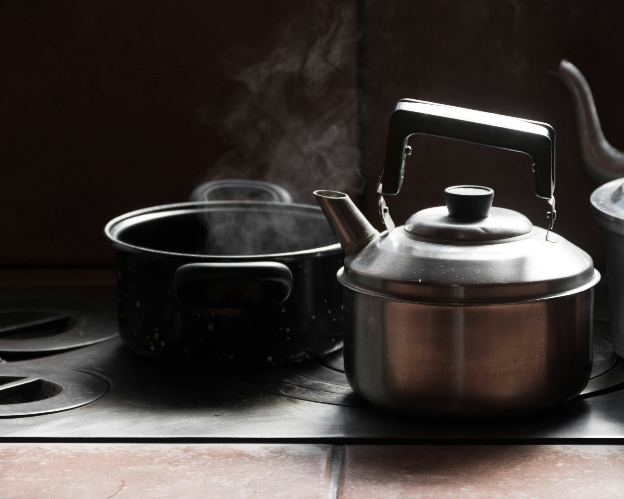 steaming pot on stove beside kettles