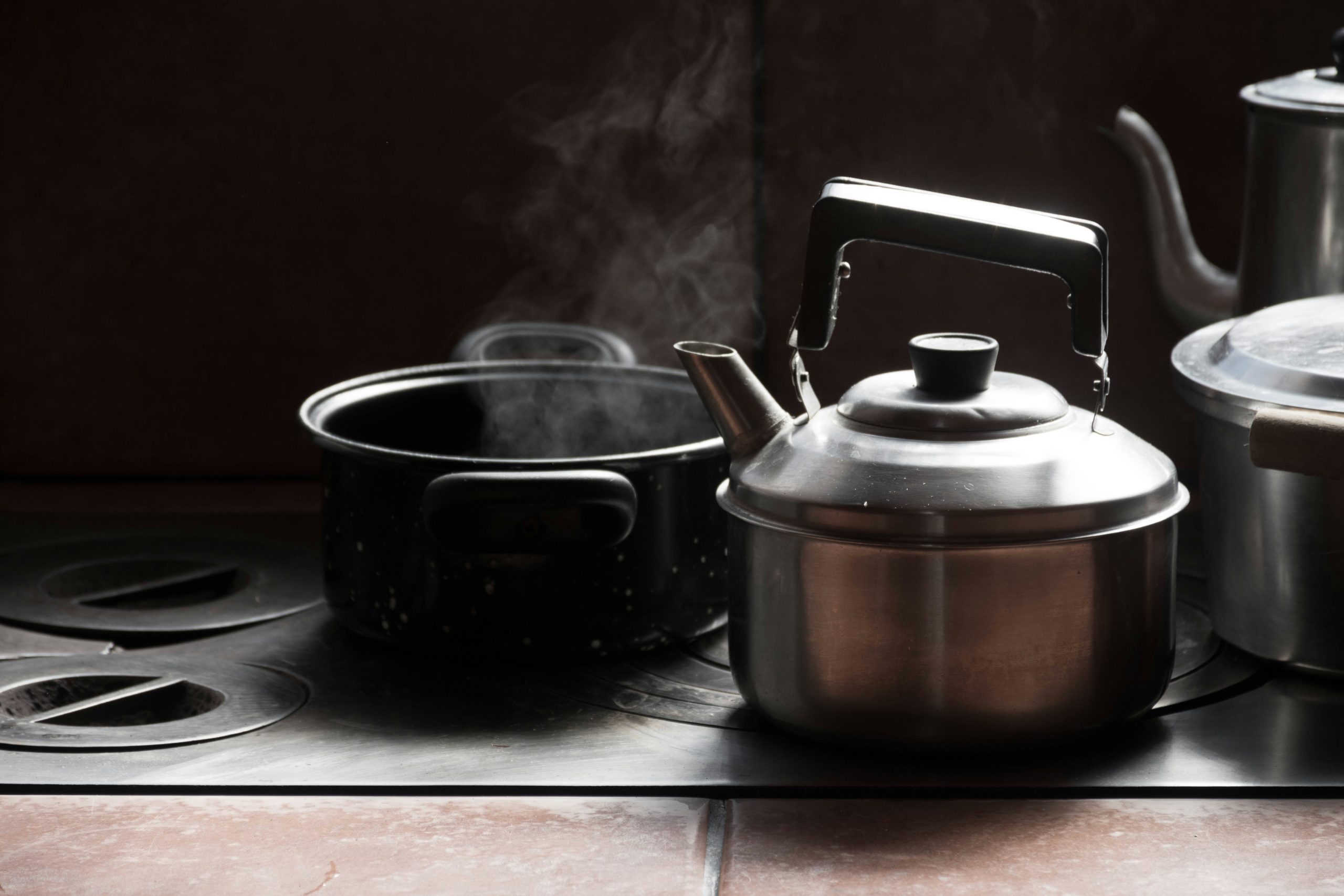 steaming pot on stove beside kettles