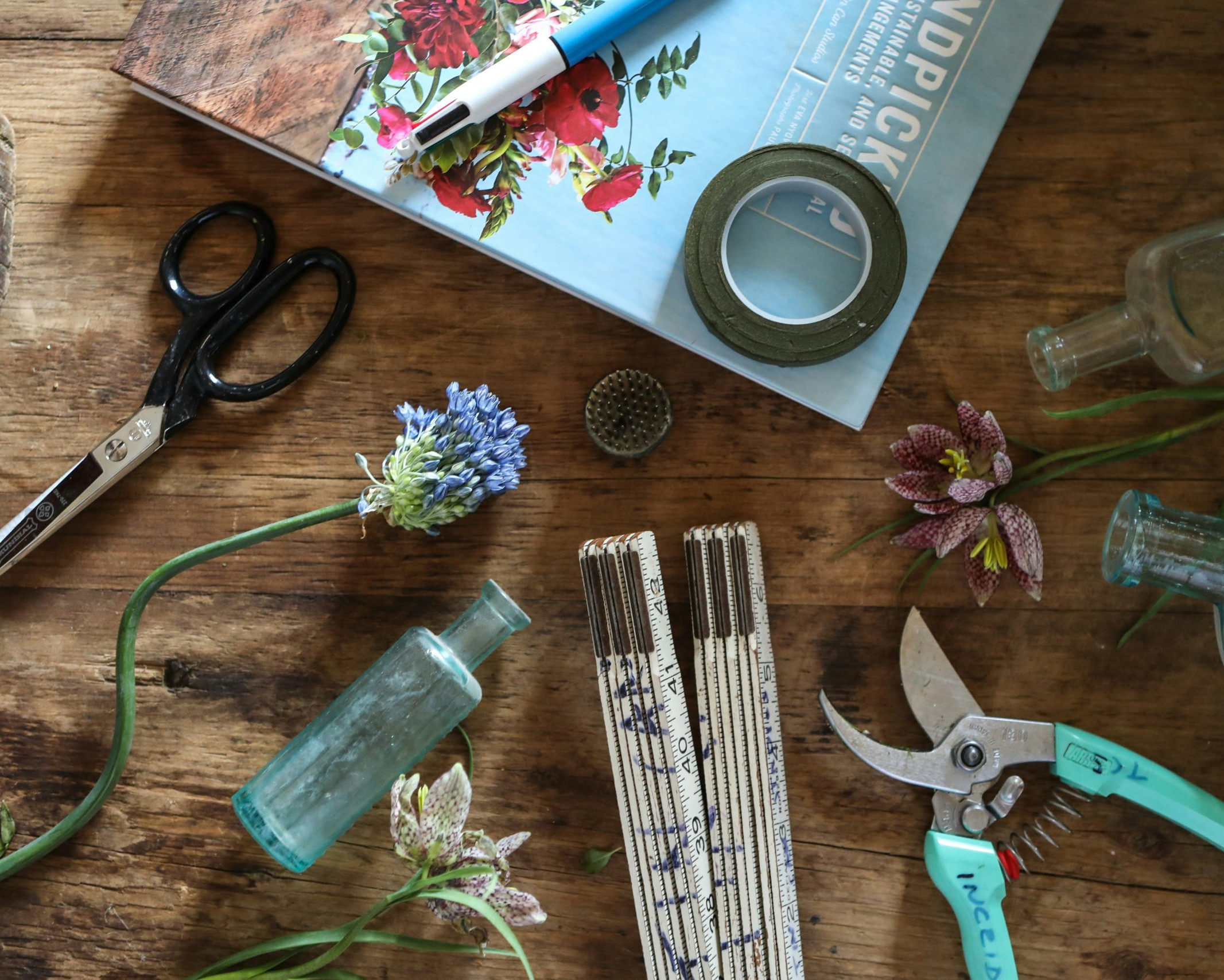 tools, snipped flowers, and a book on a wood table