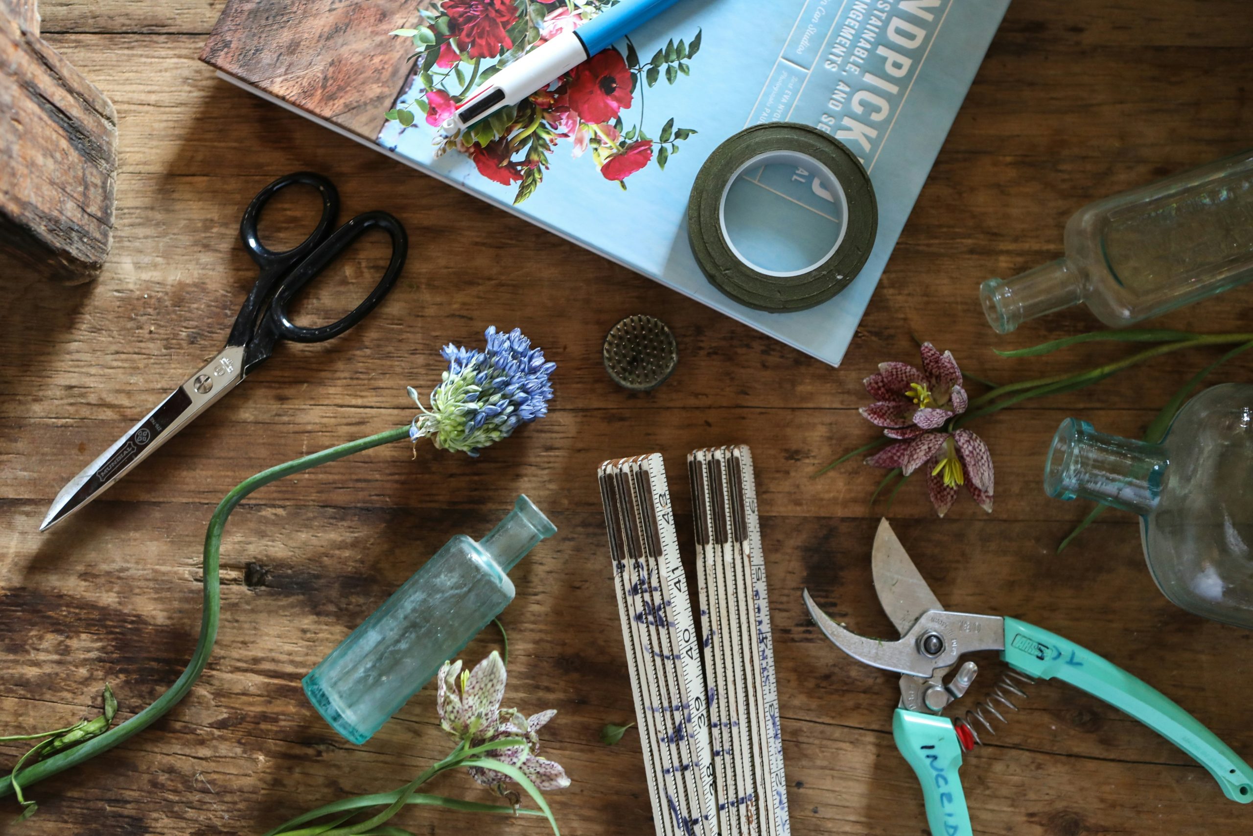 tools, snipped flowers, and a book on a wood table