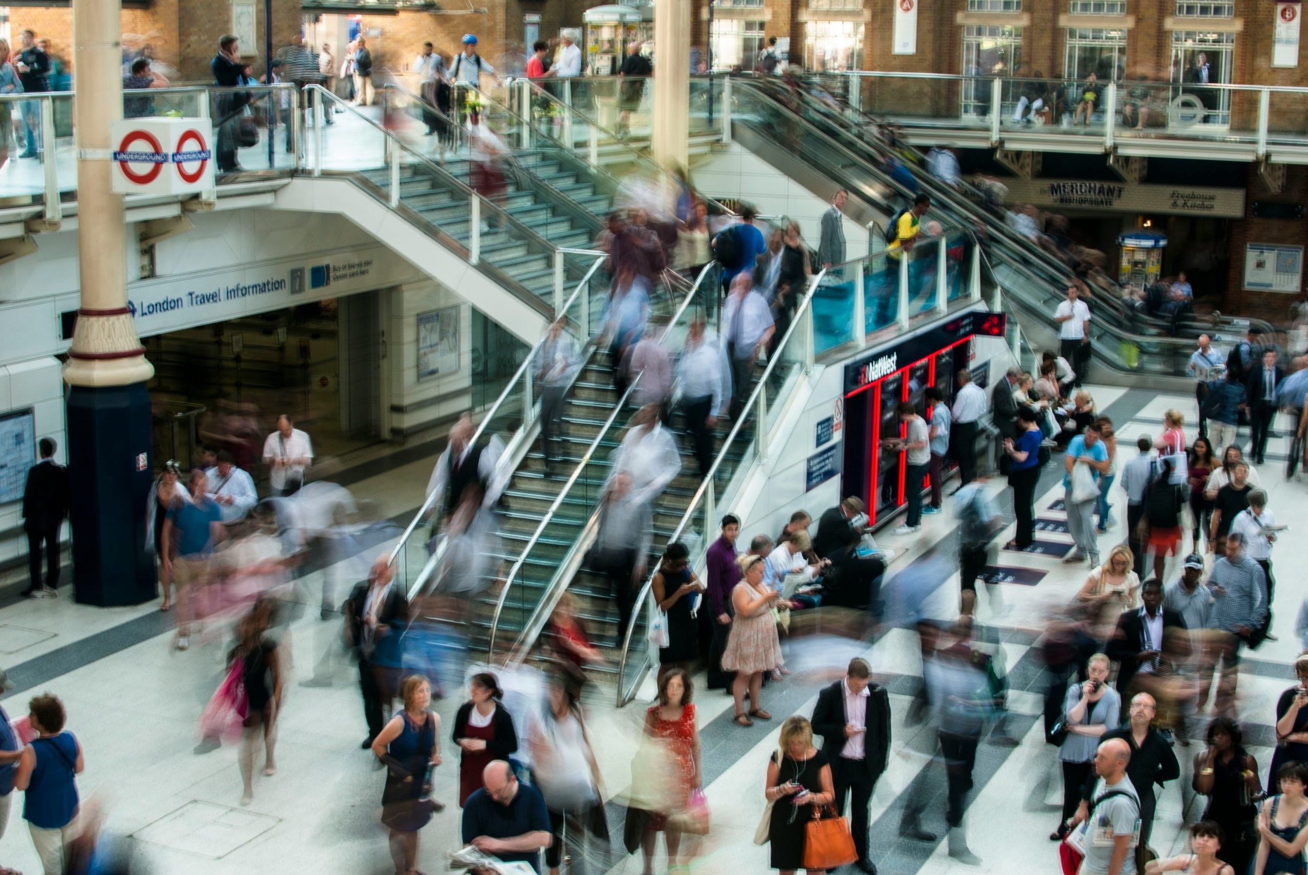 people on escalators in a crowded shopping mall