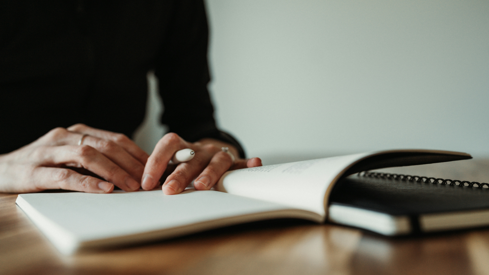 person with pen and notebook sitting at a table